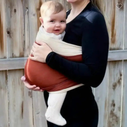 A mother embraces her baby in a baby carrier, allowing for hands-free mobility while keeping the child snug and secure.baby wraps baby products and baby gifts