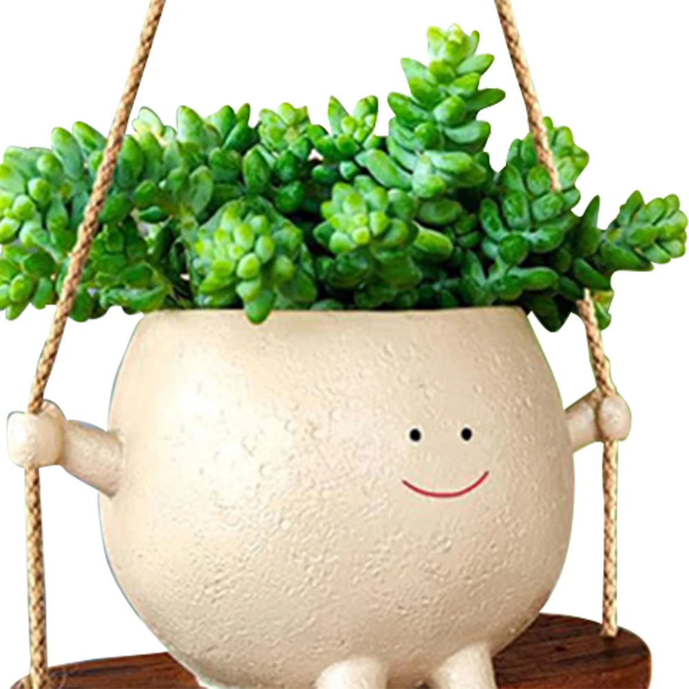 Close-up of the smiling face planter filled with succulents on its wooden swing