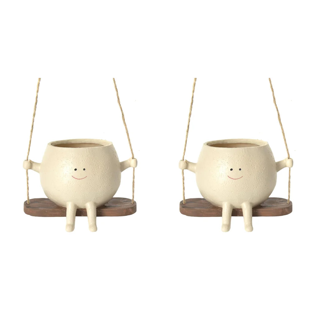 Two empty smiling face planters on rope swings side by side, white background