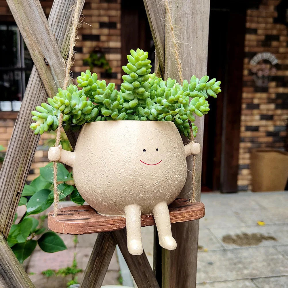Smiling face planter on a wooden swing hanging on a porch, planted with a jade succulent