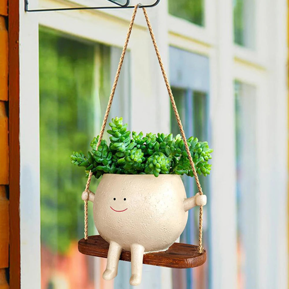 Smiling face planter with succulents hanging from a hook on a house wall
